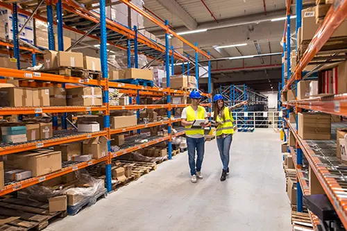 two-warehouse-workers-walking-distribution-storage-area-discussing-about-logistics-organization